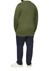 Heren olijfgroen gebreid sweatshirt met een ronde halslijn en ribbelmanchetten, gecombineerd met marineblauwe broek en witte sneakers.