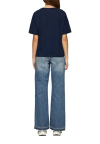 Navyblauwe katoen T-shirt met een comfortabele pasvorm, gecombineerd met lichtblauwe wijde spijkerbroek met een rafelige zoom en achterzakken.