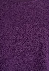 Fialová fleece látka s jemným, textúrovaným povrchom. Má okrúhly výstrih. Uniformná farba a materiál po celom povrchu.