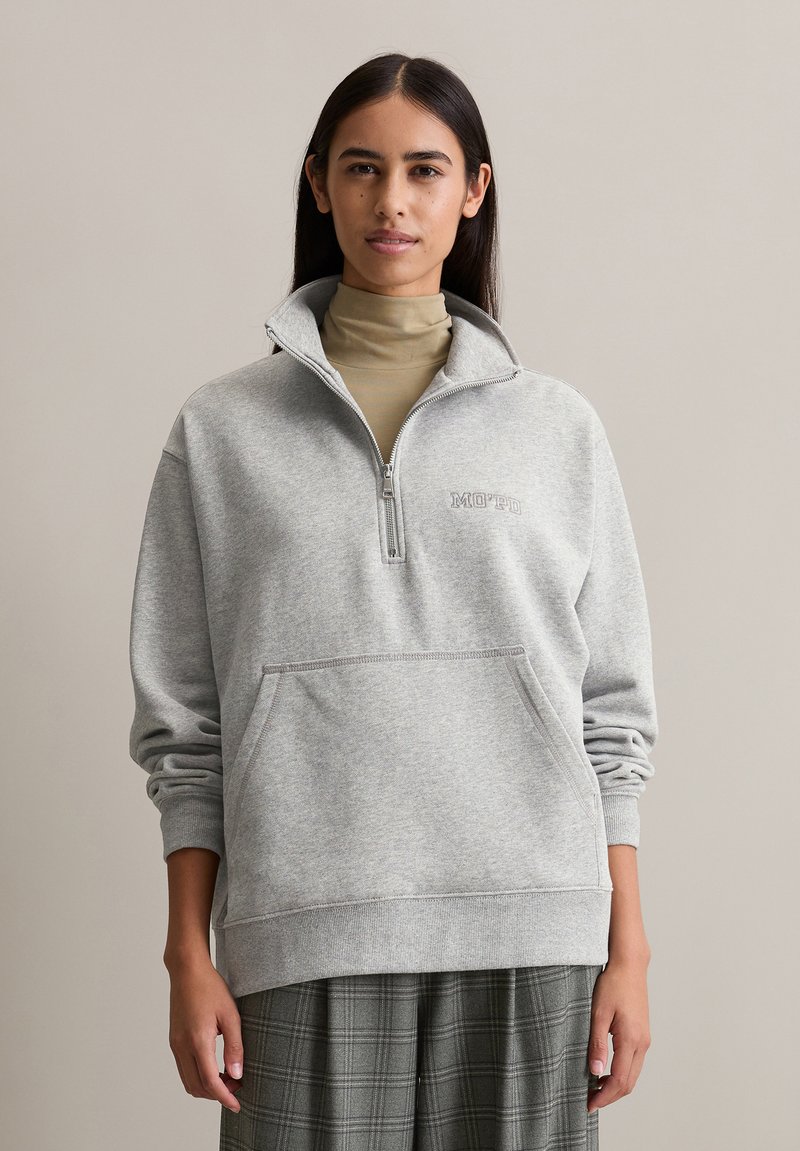 Graue Zip-Hoodie mit Stehkragen, ausgestattet mit einer Fronttasche und "MOTD" Stickerei. Weicher Baumwollmischstoff, lässige Passform, gerippte Bündchen.