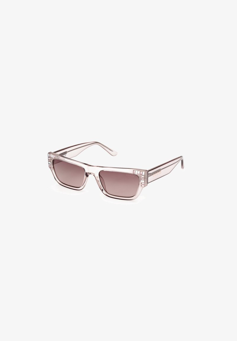 Occhiali da sole con una montatura traslucida marrone chiaro, lenti quadrate e dettagli decorativi laterali. Le lenti sfumate passano da un marrone scuro a un marrone chiaro.
