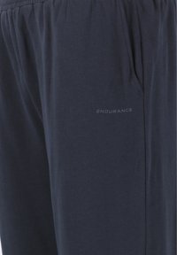 Mörkblåa mjukisbyxor i mjukt material, med elastisk midja, sidofickor och en diskret "ENDURANCE"-logotyp på låret.