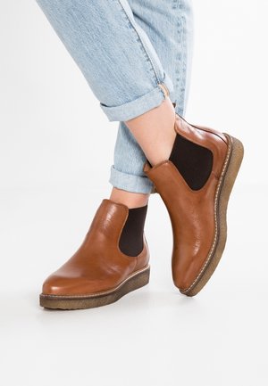 Brown leather ankle boots with elastic side panels and textured rubber soles, featuring a rounded toe and subtle stitching detail.