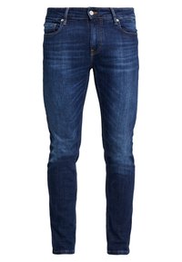 Vaqueros de mezclilla azul oscuro con un corte ajustado, que presentan un sutil desvanecimiento, diseño de cinco bolsillos y herrajes metálicos en la cintura.