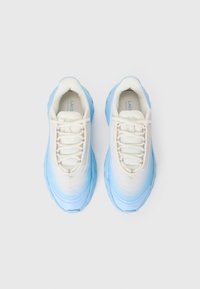 Une paire de baskets blanches et bleu clair avec un design à lacets et des semelles épaisses, présentée de dessus sur fond blanc.