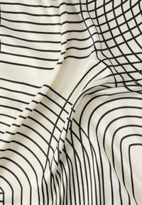 Ύφασμα σατέν με κρεμ φόντο που διαθέτει έντονες μαύρες γραμμές που σχηματίζουν συγκεντρικά καμπυλωτά σχήματα, δημιουργώντας ένα μοντέρνο γεωμετρικό μοτίβο.