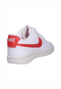 Baskets en cuir blanc avec des accents rouges. Présentent un col rembourré, un côté texturé et une semelle en caoutchouc avec des détails mouchetés. Marque Nike à l'arrière.