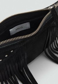 Portafoglio in suede nera con chiusura a zip, presenta dettagli frangiati e piccoli borchiette metalliche. L'interno è foderato in tessuto e ha un'etichetta del marchio.