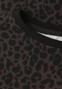 Svart och brun leopardmönstrad tyg med en ribbad struktur, som har en svart rund hals och sömnadsdetaljer.