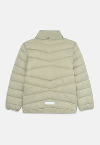 Veste isolée vert clair avec un col montant, présentant un motif matelassé en chevrons et des poignets élastiques. Comprend une petite étiquette rectangulaire à l'arrière.