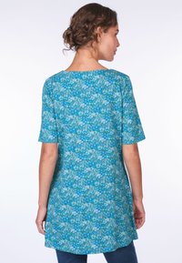 Blusen tunika mit floralem Muster in Blau und Grün, mit kurzen Ärmeln, einem runden Ausschnitt und einem leicht geschwungenen Saum für eine elongierte Silhouette.