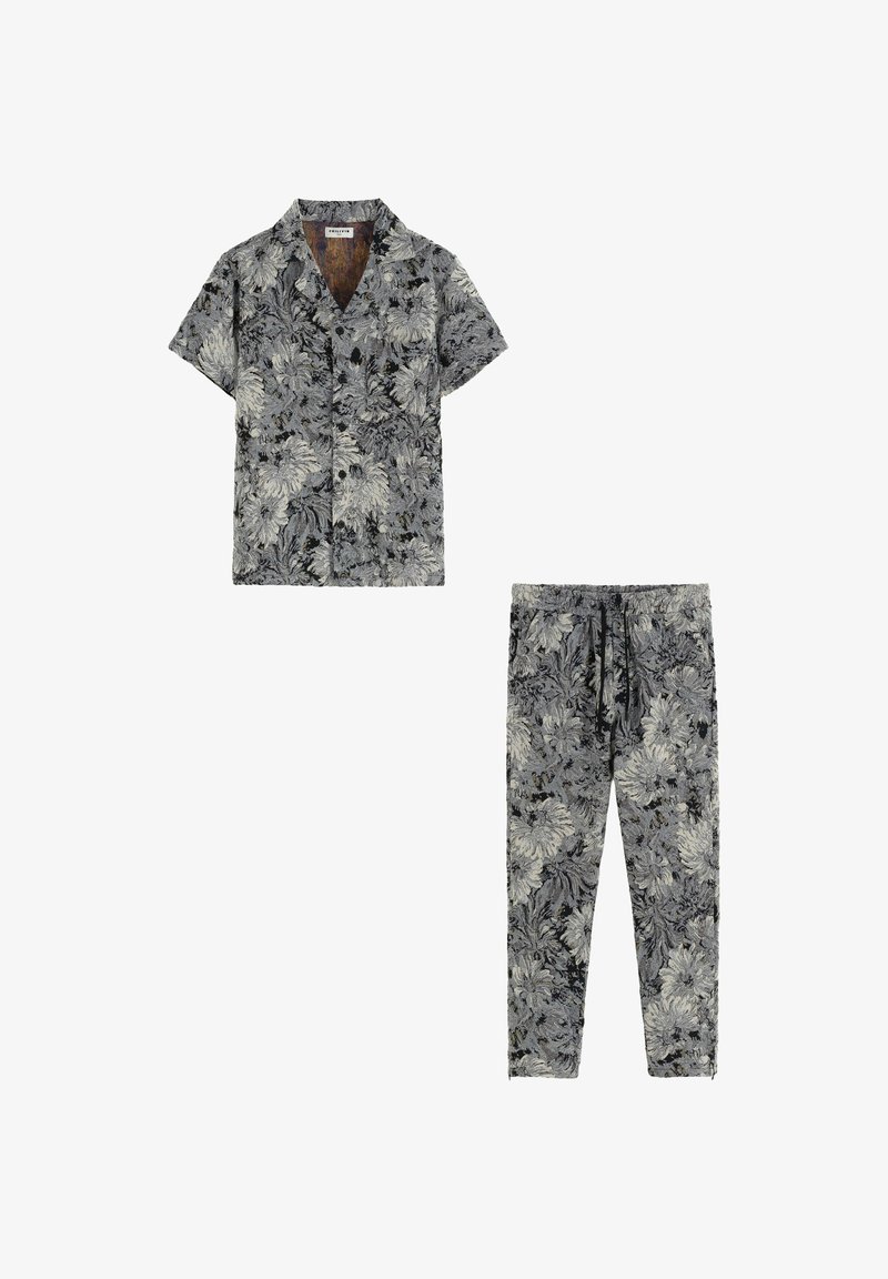 Chemise à manches courtes avec boutons et pantalon assorti en motif floral noir et blanc ; tissu léger avec une coupe décontractée et taille élastique à cordon.