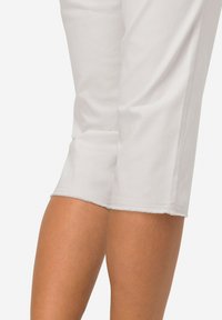 Witte capri-broeken met een gladde textuur, voorzien van een gestikte zoom en een getailleerd ontwerp, waarbij een deel van het been zichtbaar is.