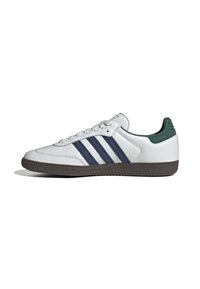 White sneaker with navy blue stripes, textured rubber sole, and green accent on the heel. Made from smooth leather with a lace-up design.