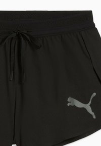 Shorts de sport noirs avec taille à cordon et logo Puma réfléchissant sur la partie inférieure de la jambe droite.