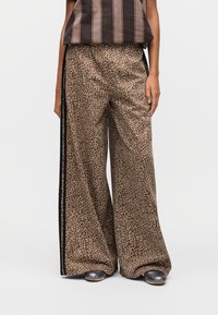 Wide-leg trousers in brown fabric with a textured leopard print, featuring black side stripes and a smooth, shiny finish.