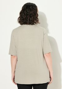 Camiseta de manga corta en color beige claro con un ajuste relajado. Tejido suave y liso con cuello redondo y dobladillo recto. Diseño minimalista.