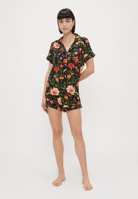 Pijamas curtos florais com um fundo preto e flores coloridas, mangas curtas, fecho de botões à frente e calções combinando.