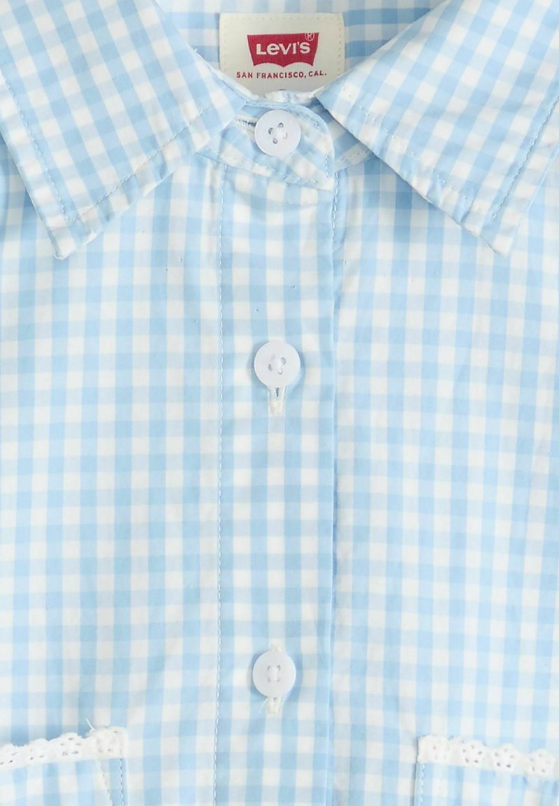 Chemise Levi's à carreaux vichy bleu clair et blanc avec boutons blancs et bordure en dentelle sur les bords inférieurs.