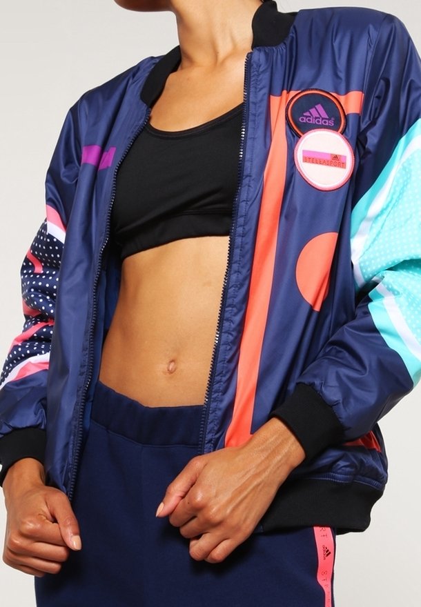 Navy bomber jacket with multi-colored accents in pink, blue, and white. Features a ribbed collar, zip closure, and distinctive logo patches.