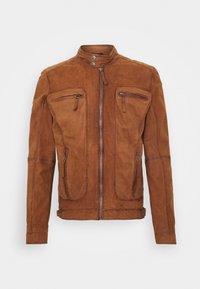 Giacca in suede marrone con zip frontale, colletto alto con due bottoni a pressione e quattro tasche con zip, esposta su sfondo neutro.