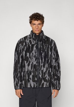 Fleece jacket in black and gray with a textured pattern, full zip, high collar, and relaxed fit. Features long sleeves and pockets.