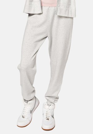 Helle graue Jogginghosen aus weichem, elastischem Material mit lockerer Passform. Kombiniert mit weißen High-Top-Sneakern mit grauen Akzenten.