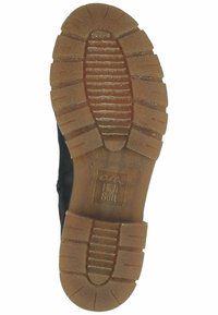 Suela de zapato negra con una superficie texturizada y de goma. Presenta surcos profundos para tracción y un diseño marrón, estampado para un mejor agarre.