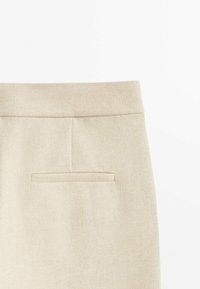 Beige tailored skirt with a smooth textured finish, featuring a small back pocket and a clean waistband design.