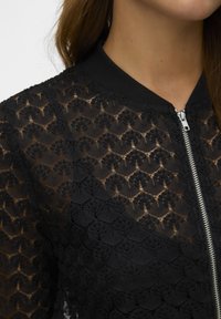 Black lace bomber jacket with a ribbed collar, featuring a floral pattern, metallic zipper, and sheer texture.