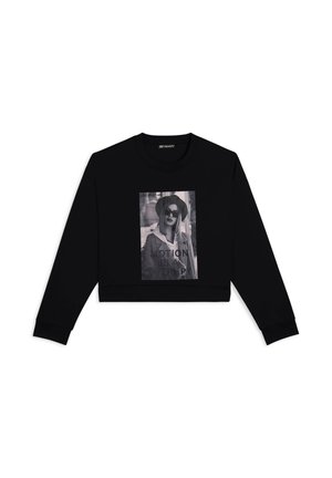 Sweatshirt court noir avec un grand imprimé graphique monochrome portant le texte "MOTION IS A THING" et un modèle portant des lunettes de soleil.