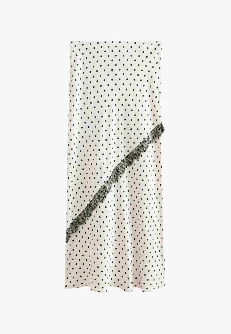 Jupe blanche à pois noirs avec une bordure en dentelle noire diagonale à l'avant.