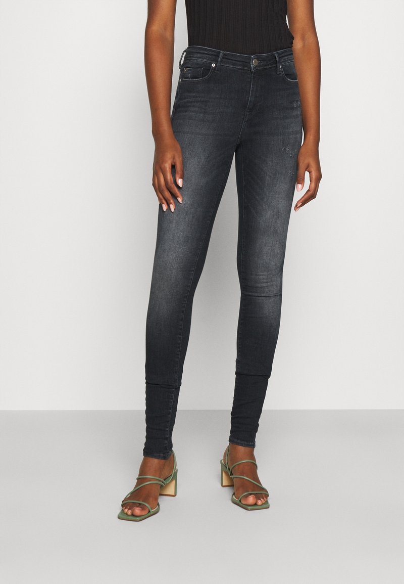 Jeans ajustados en denim oscuro, con una silueta ajustada, diseño de cinco bolsillos, un ligero desgaste y una textura suave.