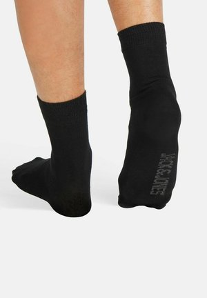 Black cotton crew socks with ribbed cuffs and a smooth texture, featuring a subtle logo printed on the side. No patterns or accents.