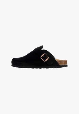 Sabots en daim noir avec une semelle en liège, dotés d'une sangle ajustable et d'une boucle en métal. Le design est simple et discret.
