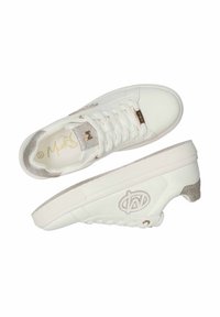 Bílé tenisky s metalickými zlatými akcenty. Hladký kožený svršek, třpytivý jazyk a strukturovaná podrážka. Na boku se nachází logo.