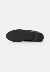 Semelle de chaussure en cuir noir avec une surface texturée, présentant un motif de grip et un talon lisse, conçue pour l'adhérence et la durabilité.