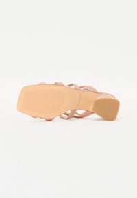 Rosa hæl sandal med teksturerte stropper og en glatt s�åle. Har en firkantet hæl og en sklisikker gummibunn for godt grep.