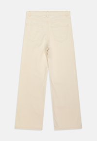 Beige vide benbukser med en glat tekstur, der har to baglommer og lige kanter. Afsluttet med bæltestropper og simpel syning.