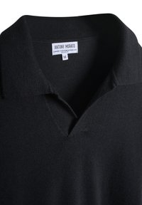 Polo shirt in cashmere e lana nera con colletto a V, con etichetta interna che riporta il nome del marchio e la taglia "M". Texture morbida.