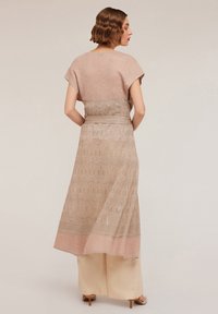 Beige long dress with short sleeves, textured fabric featuring a zigzag pattern, and a contrasting pink hem. Tied belt accentuates the waist.