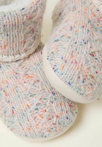Gestrickte Hausschuhe mit einem mehrfarbigen Garnmuster, weicher Wolltextur und einer weißen Gummisohle. Knöchelhohes Design mit einem gemütlichen Finish.