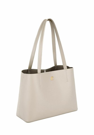 Bež usnjena torba z dvema naramnima trakoma in majhnim zlato barvnim logotipom na sprednji strani, prikazana na belem ozadju.