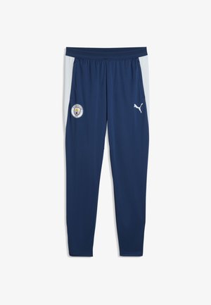 Granatowe spodnie sportowe z jasnoszarymi panelami bocznymi, z logo Manchester City na lewej nodze i białym logo Puma na prawej nodze.