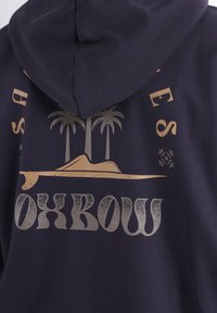 Hoodie bleu marine avec un graphique doré représentant des palmiers et une montagne. Le texte "Oxbow" est inscrit dans une police usée. Tissu doux, poche kangourou.