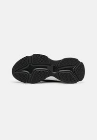 Schwarze Sport-Schuhsohle mit einer strukturierten Gumm-Oberfläche, die Zickzackmuster und ein ausgeprägtes Fußgewölbe-Design für besseren Halt aufweist.