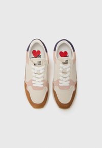 Stijlvolle sneakers met een lichtbeige bovenzijde, roze en bruine accenten, en een paarse hiel, met "LOVE MOSCHINO" branding aan de binnenkant.