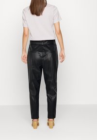 Zwarte neplederen broek met een relaxte pasvorm, voorzien van een gladde textuur, achterzakken en een riemlus middenin de taille.