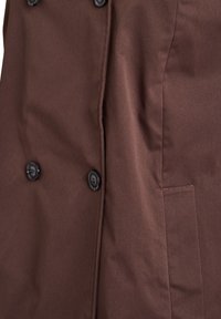 Brauner Mantel mit doppelreihigem Design, zwei schwarzen Knöpfen, einer Seitentasche und glatter Stoffstruktur.