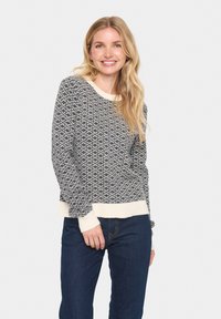 Kootud sviiter, millel on must-valge geomeetriline muster, ümmargune kaelus, soonilised mansetid ja hem, vabalt langev lõige.